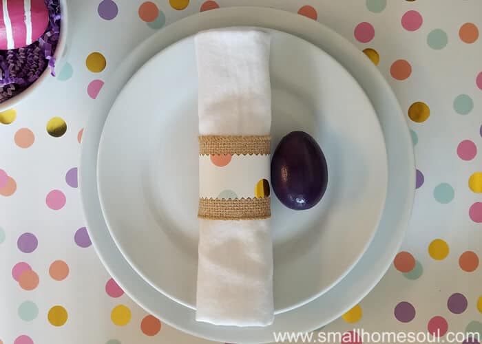 Easter table decorations with burlap ribbon wrapped around a cloth napkin.