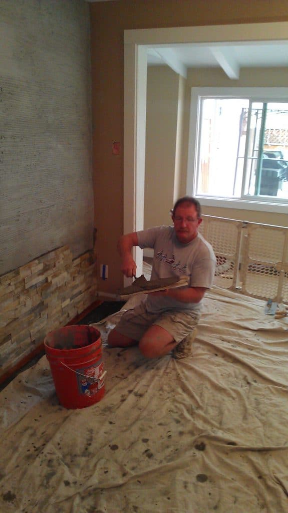 Buttering back of quartz tile with mortar to apply to wall.