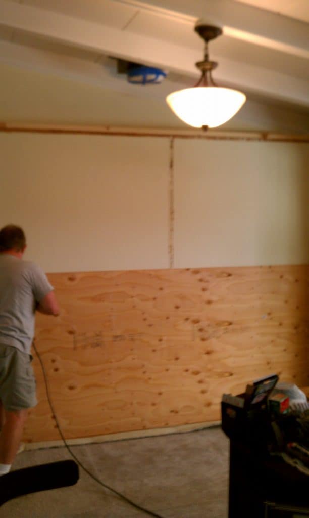 Screwing plywood to wall to prep for quartz wall insallation.