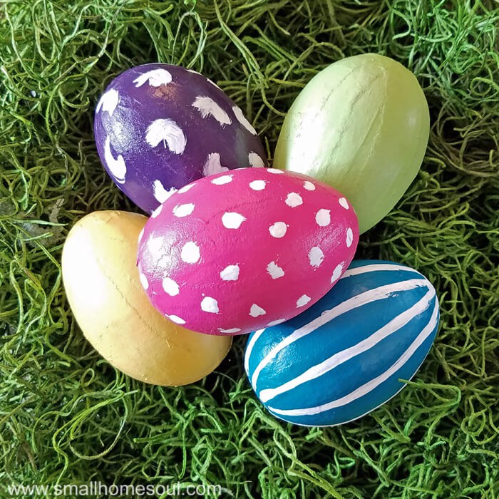 Completed painted easter eggs in purple pink teal yellow green on green moss.